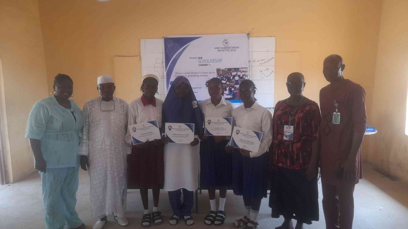 Students holding their KHI Scholarship certificates in front of the project banner